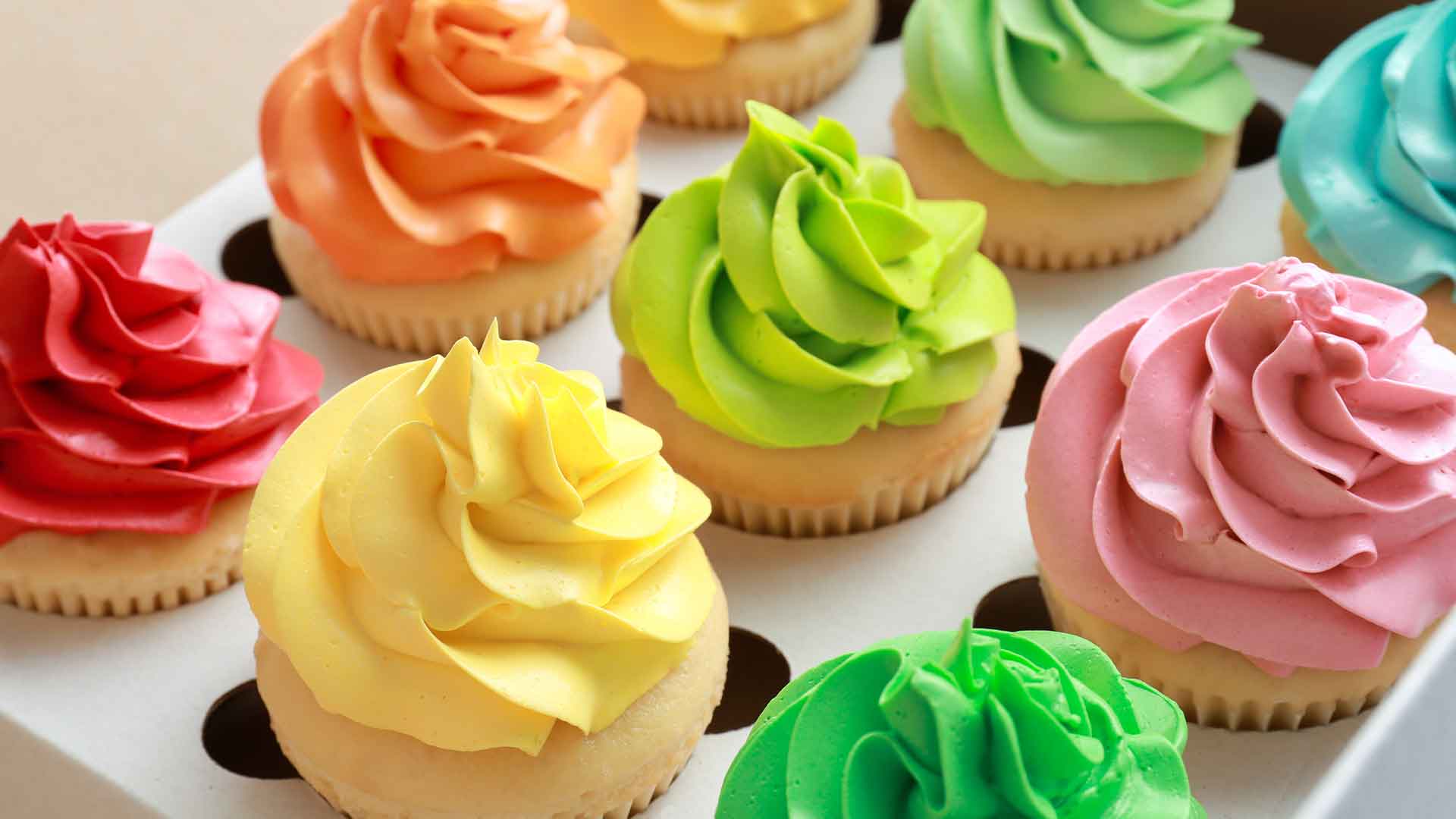 Assorted colorful cupcakes on a white tray