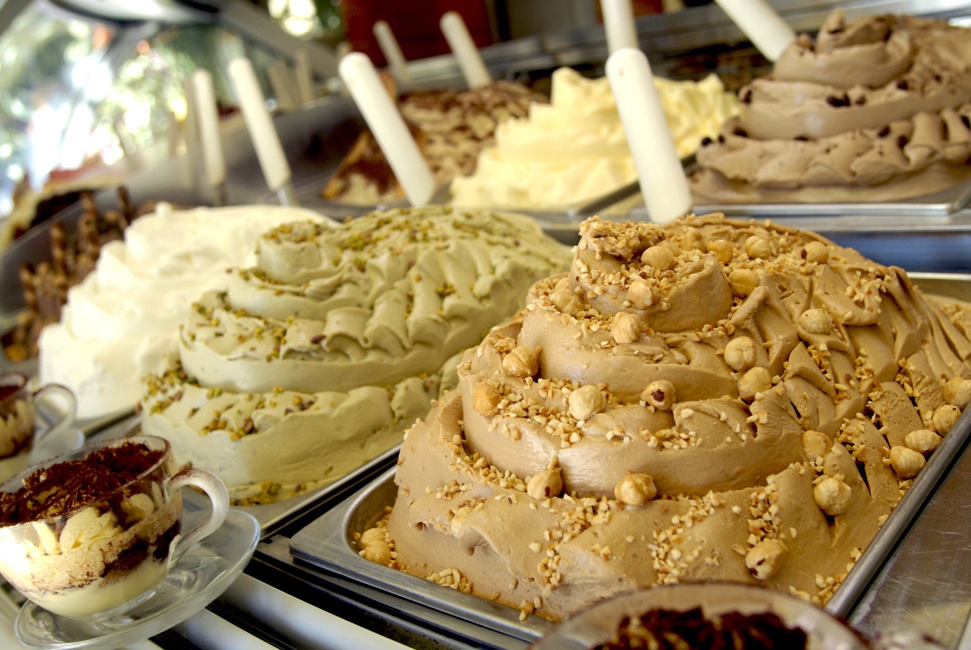 Close-up of various ice cream desserts with different toppings in a display case.