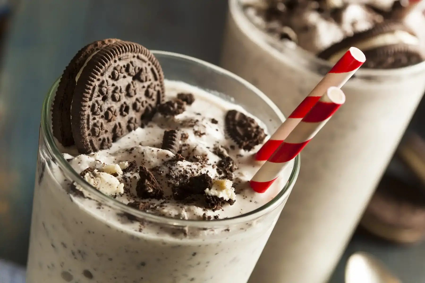 Cookies and cream milkshake with an Oreo cookie and a red and white straw.
